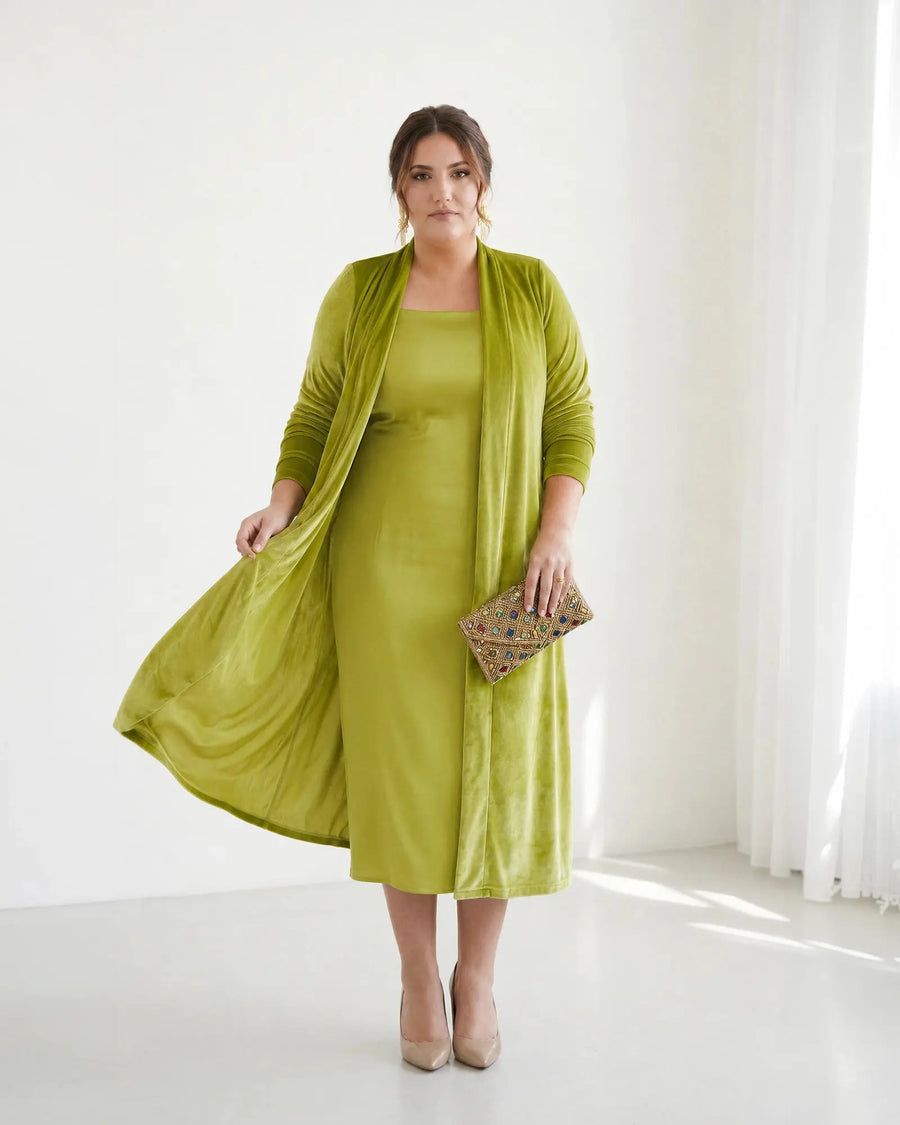 Chaqueta larga Candela de terciopelo verde lima sobre vestido a juego, vista frontal con clutch de pedrería, talla grande
