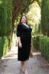 Chica morena llevando el vestido Irene de terciopelo negro, con manga abullonada y corte midi