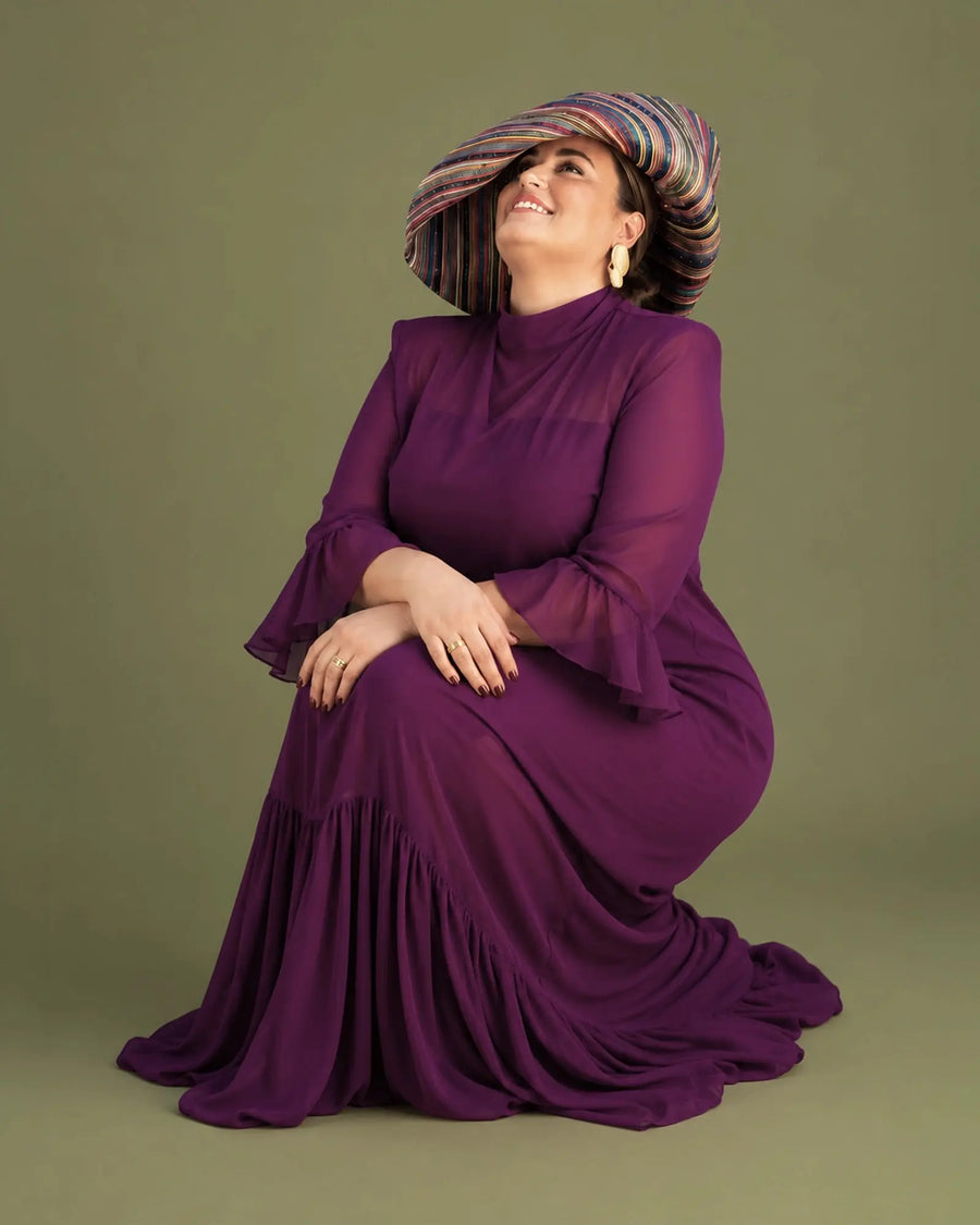 Vestido Marina de gasa color buganvilla con cuello alto y mangas de campana, modelo sentada sonriendo, talla grande