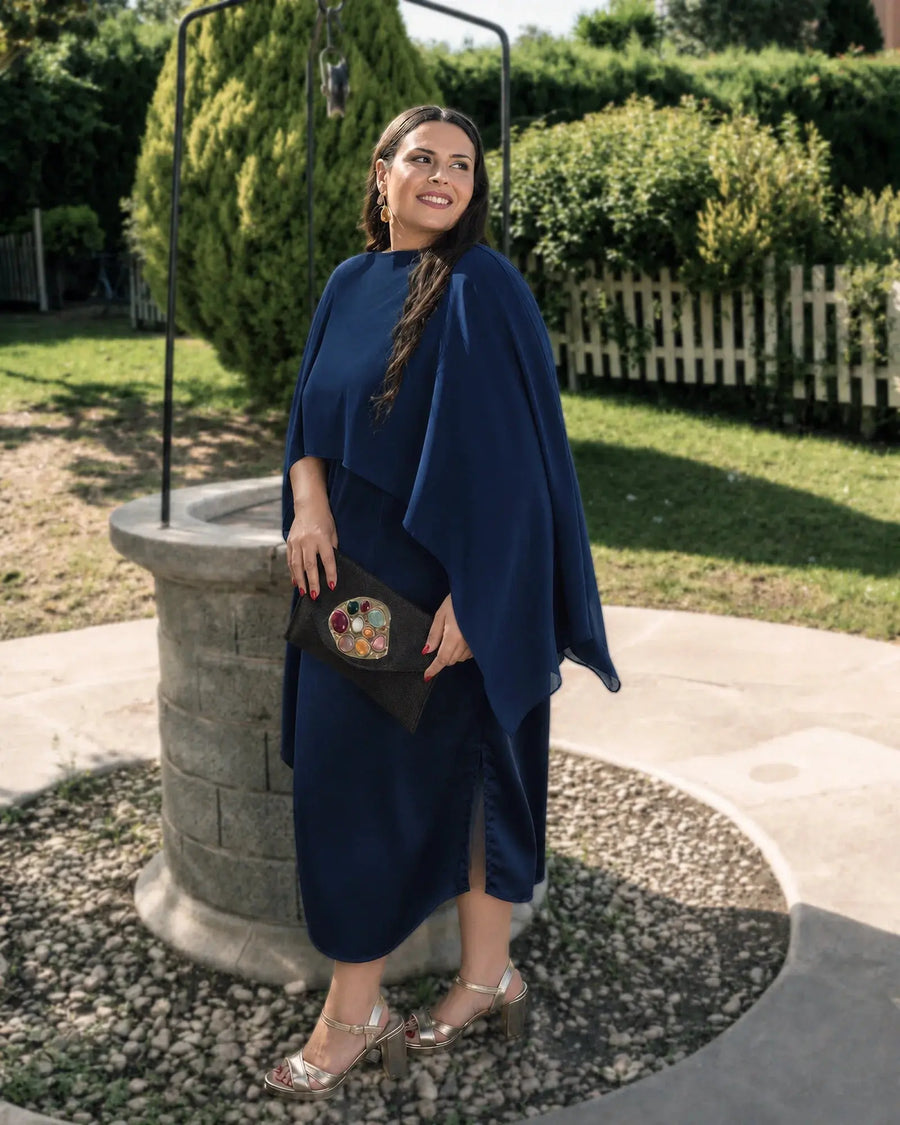 Vestido Mercedes azul marino con capa asimétrica sobre un hombro, look de invitada en exterior, talla grande