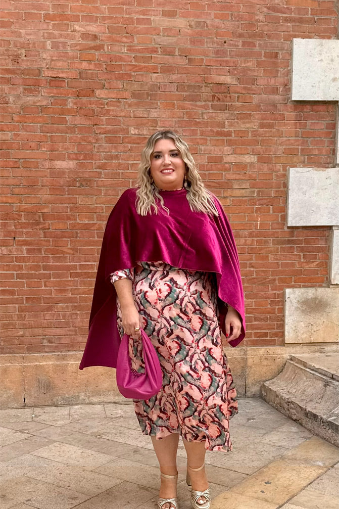 Mujer con curvas luce capa de terciopelo fucsia en talla grande, combinada con vestido de fiesta estampado y bolso a juego – moda elegante Corintia