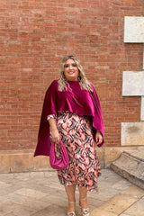 Mujer con curvas luce capa de terciopelo fucsia en talla grande, combinada con vestido de fiesta estampado y bolso a juego – moda elegante Corintia