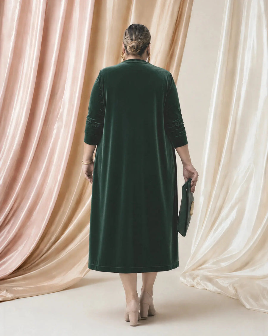 Chaqueta de terciopelo Candela en verde botella, vista de espalda, fondo de telas satinadas rosa y champán, tallas grandes