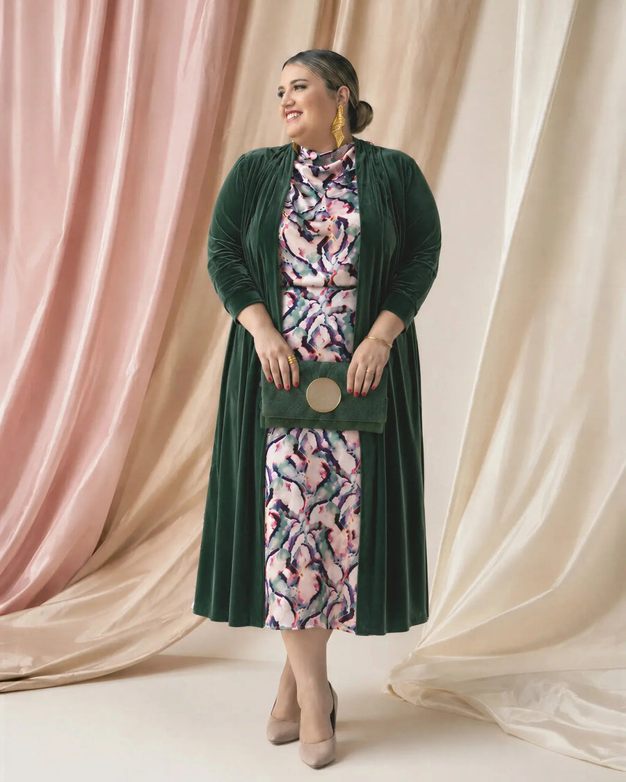 Chaqueta de terciopelo Candela en verde botella sobre vestido estampado, vista frontal sonriendo, invitada talla grande