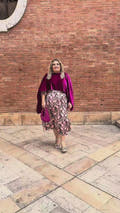 "Vídeo de mujer con curvas luciendo capa de terciopelo fucsia en talla grande, combinada con vestido de fiesta estampado y bolso a juego – look elegante Corintia