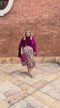 "Vídeo de mujer con curvas luciendo capa de terciopelo fucsia en talla grande, combinada con vestido de fiesta estampado y bolso a juego – look elegante Corintia